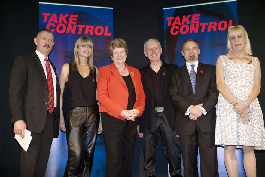 Photo of 6 people in front of the World Aids Day event banners at Customs House in 2014
