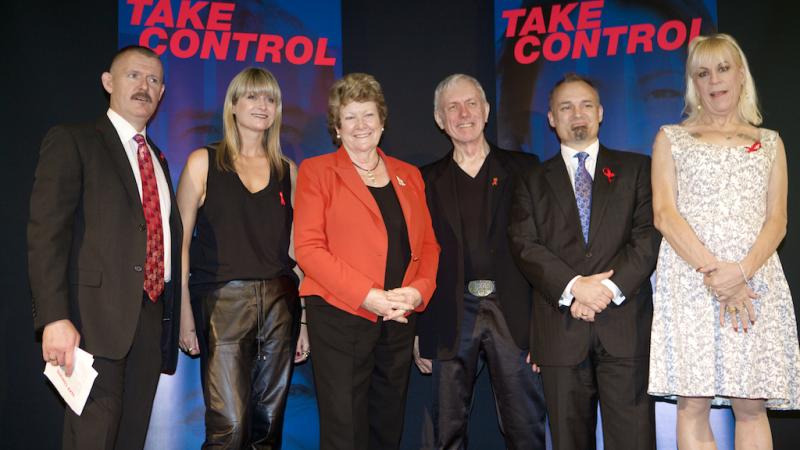 Photo of 6 people in front of the World Aids Day event banners at Customs House in 2014