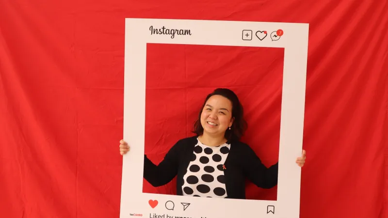 Photo from 2022 World Aids Day celebrations in Tasmania, featuring a woman posting in front of a red background